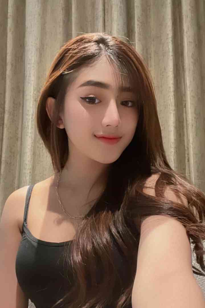 Young woman with long brown hair, wearing a black tank top.